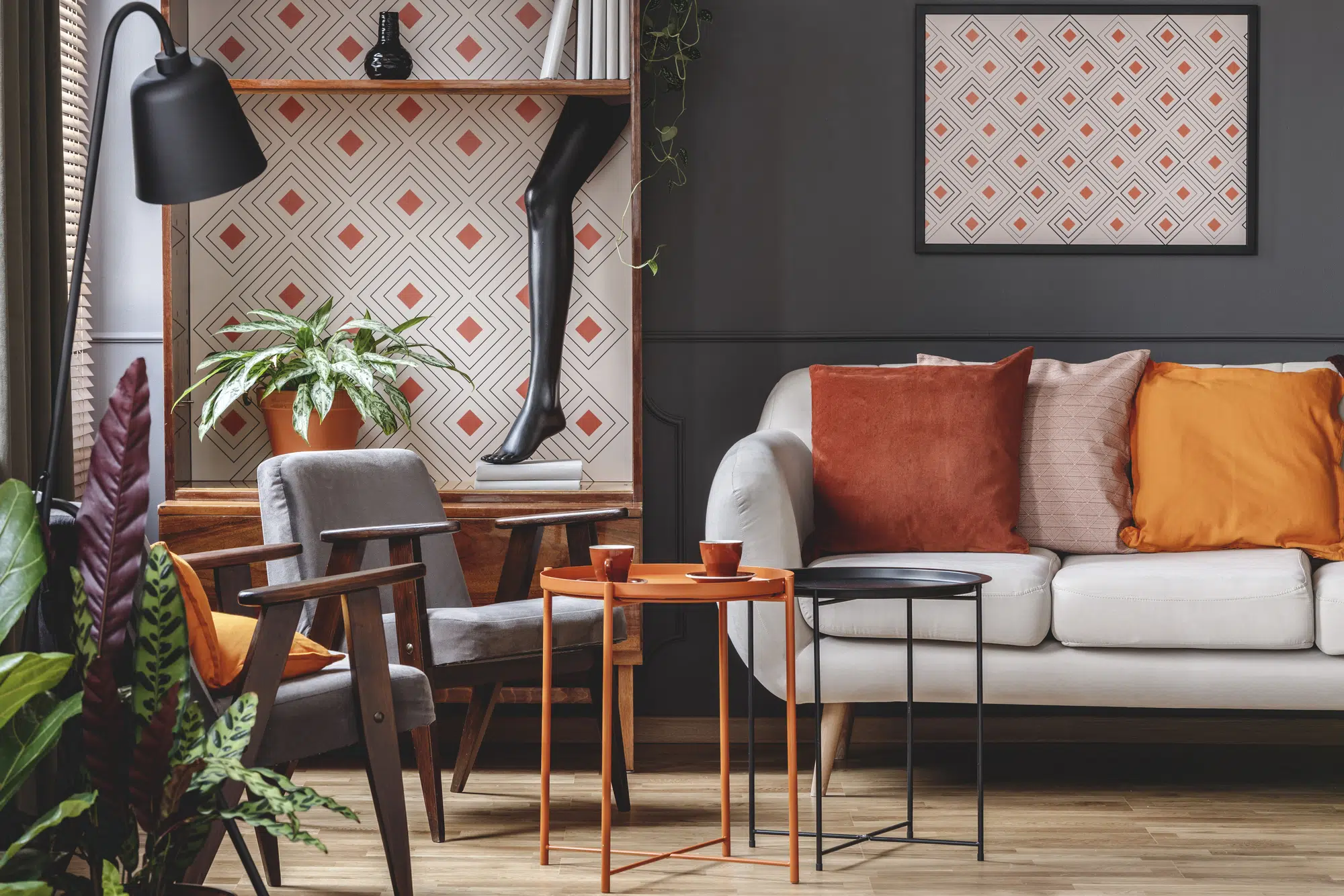Sofa with orange pillow next to table and armchair in patterned living room interior