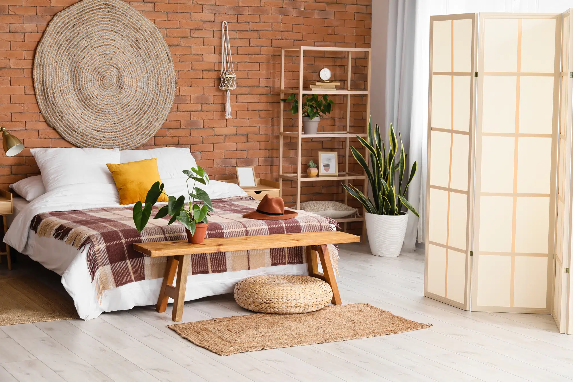 Interior of stylish bedroom with folding screen and wooden bench