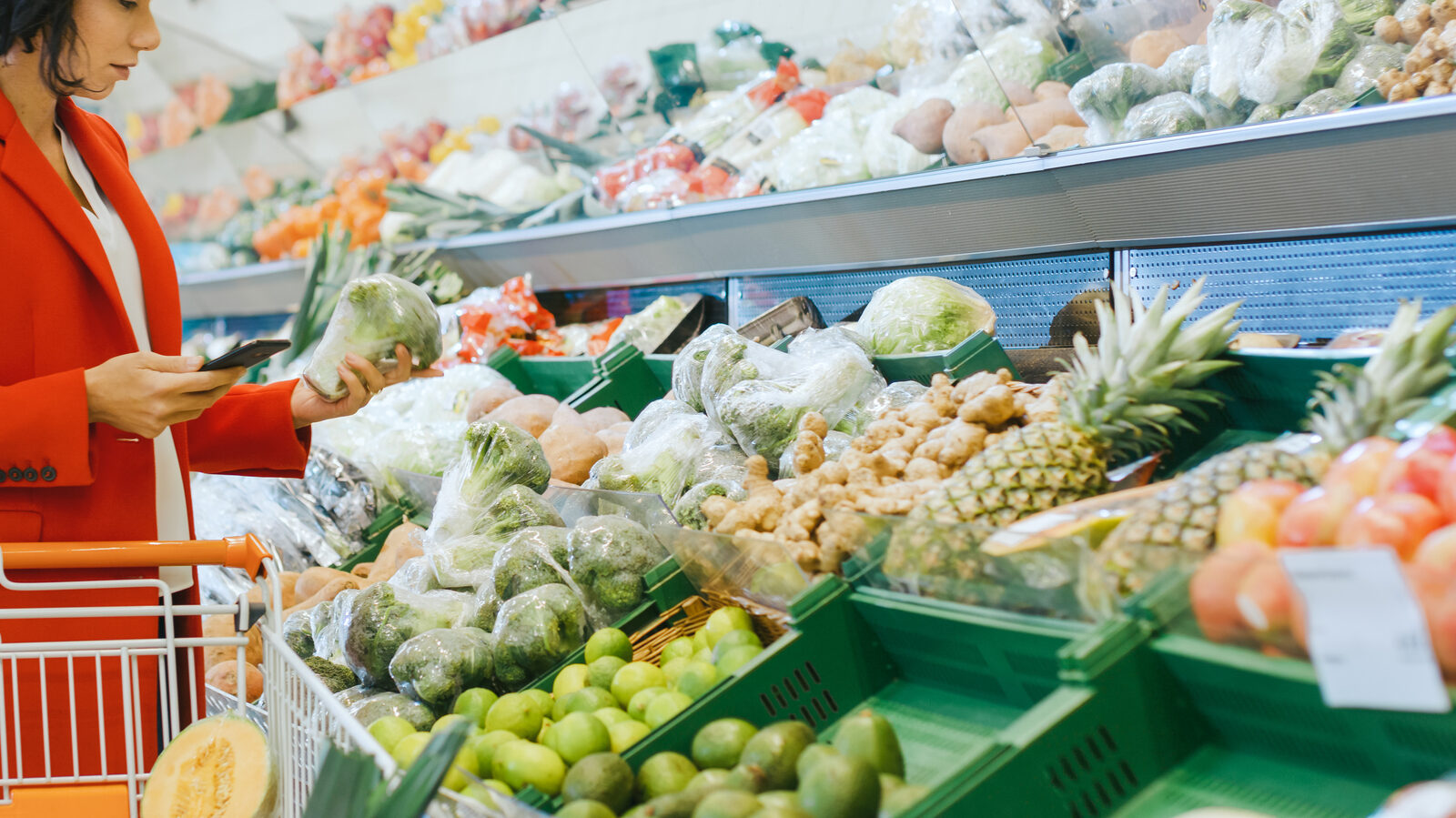 At the Supermarket: Shot of a Beautiful Young Woman Walks Through Fresh Produce Section, Chooses Broccoli and Puts them in Her Shopping Cart.