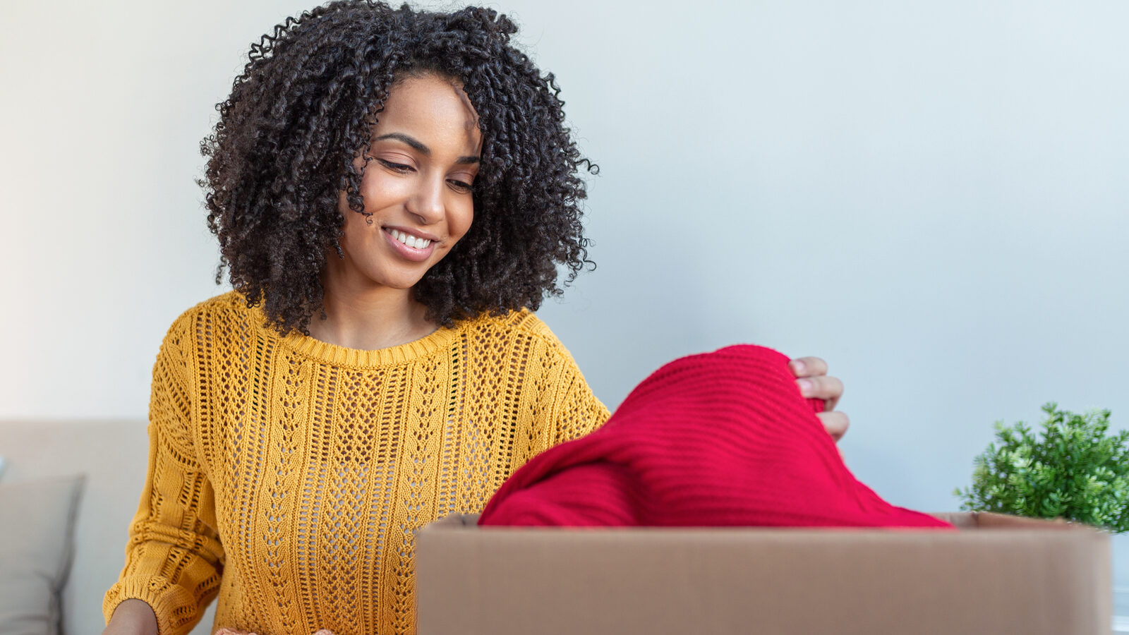 Donation Concept. Woman holding a Donate Box with full of Clothes. Woman holding a book and clothes donate box. Clothes in box for concept donation and reuse recycle