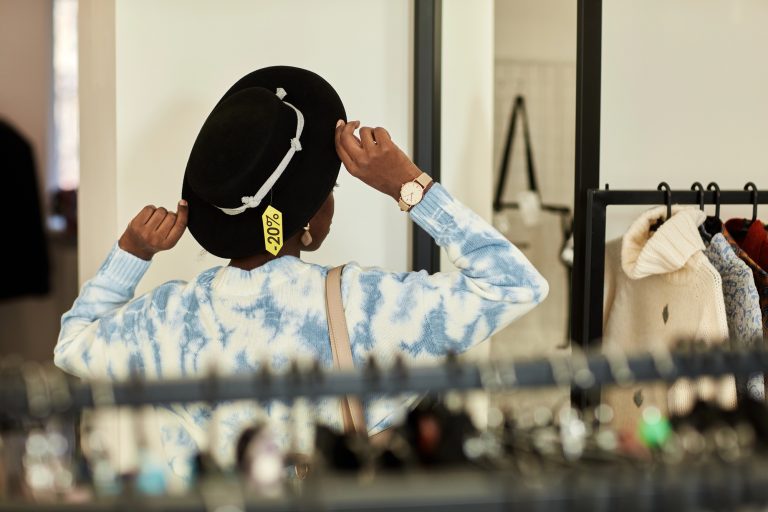 woman thrifting putting on hat while shopping